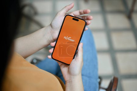 Photo for Chiang Mai, Thailand - May 26 2023: A female holding a smartphone with Payoneer logo on screen. - Royalty Free Image