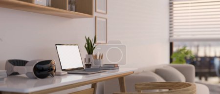 Foto de Vista lateral cercana de una maqueta de pantalla blanca para computadora portátil, un auricular VR moderno y accesorios en una mesa en una acogedora sala de estar minimalista. 3d render, ilustración 3d - Imagen libre de derechos