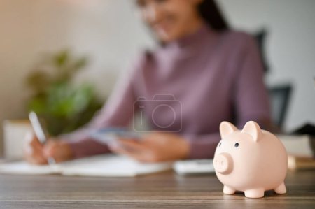 Photo for Close-up image of a piggy bank on a businesswoman's desk. savings, financial, investment, cash, coins. blurred background - Royalty Free Image