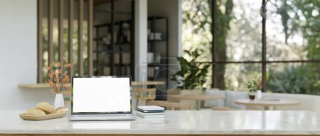 Foto de Imagen de primer plano de una maqueta de pantalla blanca portátil en una mesa con una zona de estar borrosa, moderna y acogedora cafetería como fondo. 3d render, ilustración 3d - Imagen libre de derechos
