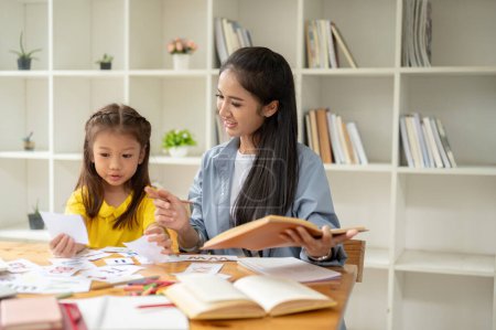 A pretty Asian preschool girl is studying the English alphabet on flashcards with a kind and caring female teacher. learning, studying, child development, parenting