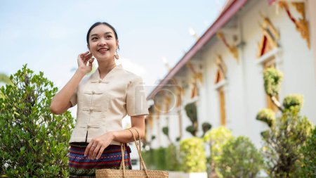 Ein Porträt einer schönen jungen thailändisch-asiatischen Frau in traditioneller thailändisch-nördlicher Kleidung befindet sich in einem wunderschönen Tempel. Thailändische Kultur, Buddhismus, Kulturreisen und Lebensstil