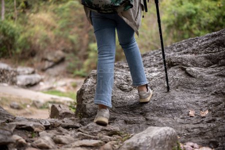 Téléchargez les photos : Gros plan jambes image d'une femme est randonnée avec un bâton de trekking sur la montagne rocheuse. exploration, aventure, voyage, activité de loisirs - en image libre de droit