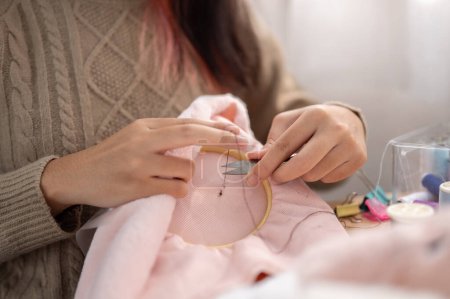 Image en gros plan d'une femme utilisant des ciseaux pour couper un fil sur un cadre de broderie, coudre à la main un motif sur un tissu, fabriquer des articles faits à la main. sertissage, tailleur, couture