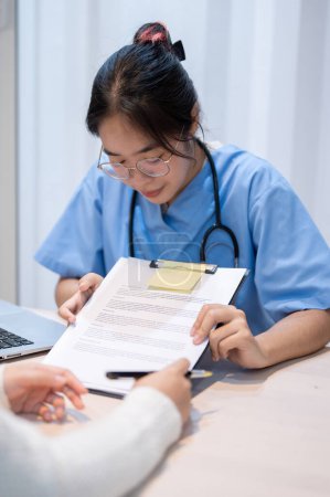 Photo for A professional Asian female doctor showing a medical checkup form or explaining a medical insurance claim document to a patient during a meeting in the office. healthcare concept - Royalty Free Image