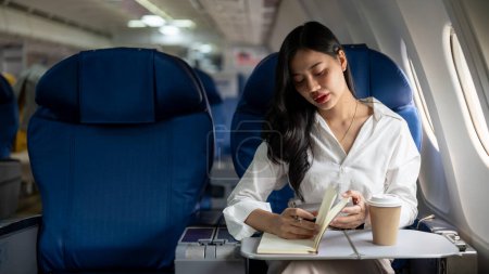 Téléchargez les photos : Une femme d'affaires asiatique séduisante et élégante est en classe affaires dans un avion, volant vers une autre ville pour une réunion d'affaires. personnes et concepts de transport - en image libre de droit