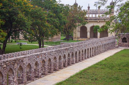 Foto de Corredor entre las estructuras de la tumba y el jardín ajardinado en Qutb Shahi Archaeological Park, Hyderabad, India - Imagen libre de derechos