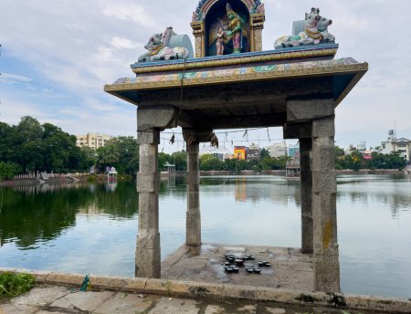 Téléchargez les photos : Chennai, Tamil Nadu, Inde - 05 décembre 2023 : Réservoir du temple de Kapaleeshwarar rempli à ras bord en raison des précipitations causées par la violente tempête cyclonique Michaung. Focus mis sur la sculpture du haut. - en image libre de droit