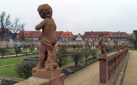 Foto de Balaustrada tallada en piedra, coronada por esculturas de un putti, en el jardín de la abadía benedictina, Seligenstadt, Alemania - 25 de enero de 2023 - Imagen libre de derechos