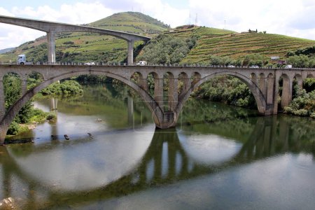 Bridges across Douro River east of Porto in the Portuguese wine region, terraced vineyards on hillslopes in the background, Peso da Regua, Portugal - May 24, 2023