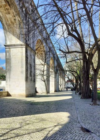 Téléchargez les photos : Arcs en pierre du tronçon Amoreiras de l'aqueduc Aguas Livres, construit au XVIIIe siècle, sentier pavé dans le jardin Amoreiras à la lumière du coucher du soleil et des ombres, Lisbonne, Portugal - 28 février 2024 - en image libre de droit