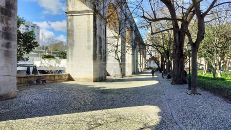 Téléchargez les photos : Arcs en pierre du tronçon Amoreiras de l'aqueduc Aguas Livres, construit au XVIIIe siècle, sentier pavé dans le jardin Amoreiras à la lumière du coucher du soleil et des ombres, Lisbonne, Portugal - 28 février 2024 - en image libre de droit