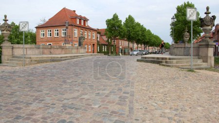 Cobblestone street on the bridge, decorated with stone-carved vases, over Ludwigsluster Canal, from the Palace Square to the town, Ludwigslust, Germany - May 3, 2012