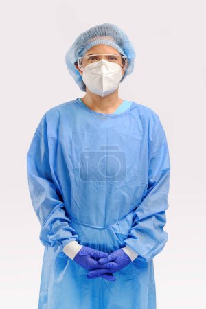 Téléchargez les photos : Portrait studio des années 40 hispanique femme chirurgien médecin ou chercheur avec un tissu protecteur complet de la robe PPE masque capuchon et gant de chirurgie isolé sur fond blanc - en image libre de droit