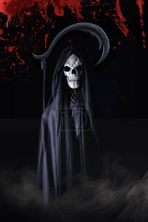 Téléchargez les photos : Portrait d'Halloween de Faucheur sombre en robe noire avec faux debout dans l'obscurité avec flux de brouillard ci-dessous avec éclaboussures et trempé de sang - en image libre de droit