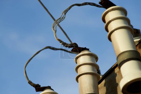 Aluminum wire screwed to an electrical transformer against blue sky