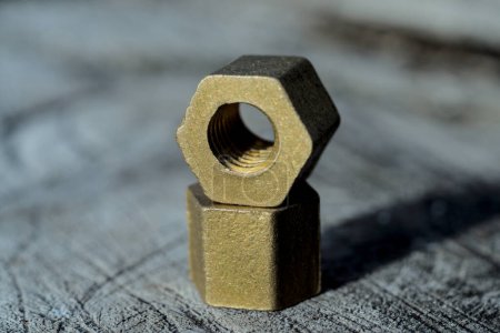 Brass hex nuts layed out on a wood, industrial background.