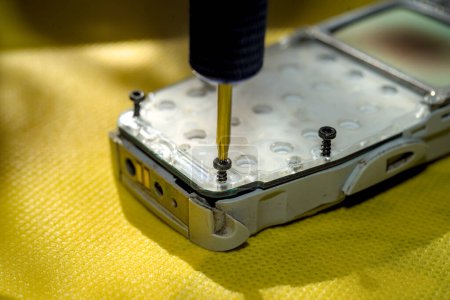 Technician disassembling components of broken phone for repair or replace new part on desk