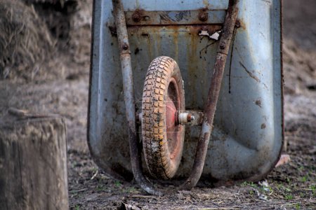 Photo of an old rusty wheelbarrow on the yard