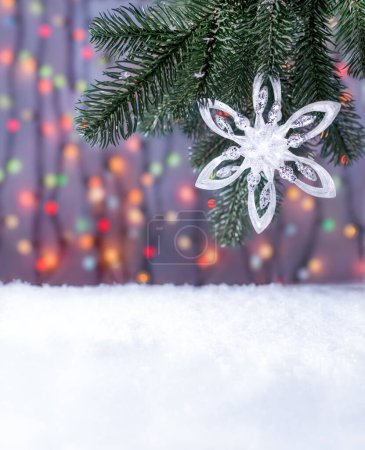 Téléchargez les photos : Décoration de Noël sur les branches vertes d'un sapin de Noël artificiel. Neige décorative sous les branches. En arrière-plan, les lumières plus froides de la guirlande sont floues. - en image libre de droit