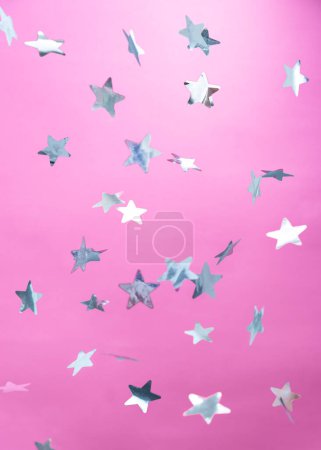 Téléchargez les photos : Confettis en forme d'étoiles argentées sur fond rose - en image libre de droit