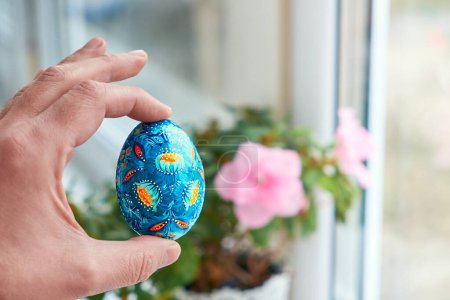 Photo for Ukrainian Easter egg with Petrykivka painting in the palm. Hand painted wooden decor. - Royalty Free Image