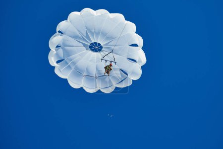 Téléchargez les photos : 07-16-2023, Bulgarie, Obzor. Parachutiste sous verrière blanche diffusant des tracts contre un ciel bleu. - en image libre de droit