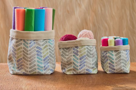 Fabric storage basket on the wooden table. Reversible cotton bin in boho style.Craft supplies storage bin.