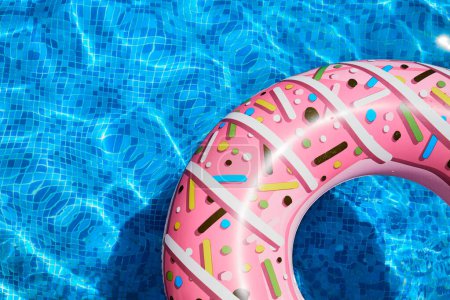 Pink inflatable ring in a blue outdoor pool. Poolside atmosphere. Pink float. Aqua party.