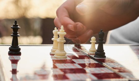Das Schachbrett ist aus Holz. Person, die Schach in der Natur spielt. Die Person hält einen schwarzen König in der Hand.