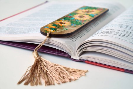 Foto de Marcador de madera con diseño floral colgado de un libro abierto - Imagen libre de derechos