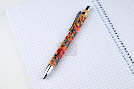 Ein klassisches Schreibwaren-Set: ein spiralgebundenes Notizbuch mit darauf liegendem Stift. Petrykivka handgemachte Malerei. Ukrainische Kunsttradition.