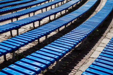 Téléchargez les photos : Des rangées de gradins en plastique bleu sur un pavé de brique attendent le public. - en image libre de droit
