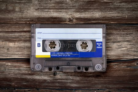 Retro cassette tape on a textured brown wooden surface.