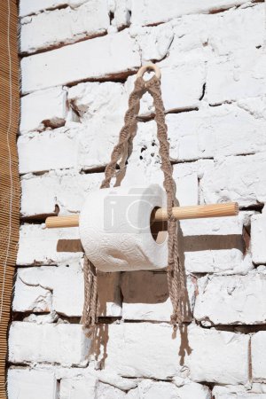 Rollo de papel higiénico colgado en una pared de ladrillo. Higiene del baño. Accesorio de camping.