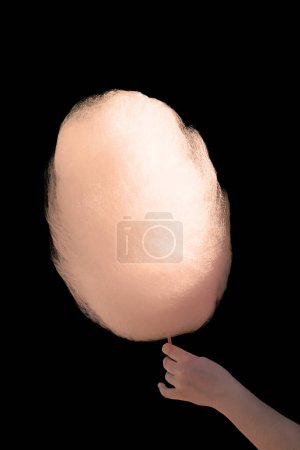 Photo for Sweet cotton candy in hand isolated on black background. The image exudes a sense of nostalgia and childlike wonder. - Royalty Free Image