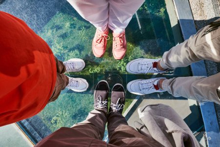 A top-down view of people's feet standing on a glass bridge.