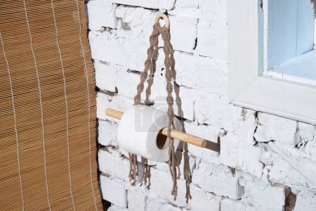 Toilet paper roll hanging on a brick wall. Bathroom hygiene. Camping accessory.