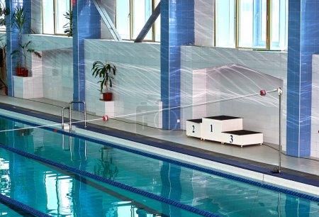 Schwimmbad mit einem weißen Siegerpodest. Türkisfarbene Schwimmbadgassen, ein Symbol des Sports.