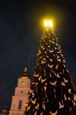 Weihnachtsbaum mit Dreizack und Dekorationen in Form von Tauben in Kiew, in der Ukraine während des Krieges. Neues Jahr 2023. Leuchtender Dreizack auf einem Weihnachtsbaum in Kiew
