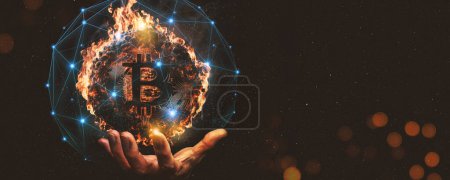 Business Human hand showing a burning bitcoin on dark background.