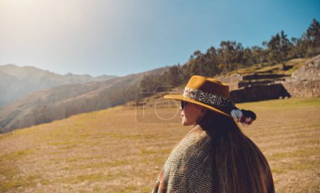 Foto de Elegante chica hipster en sombrero caminando por la cima de las montañas. Mujer joven y feliz con mochila explorando montañas soleadas. Concepto de viaje y vagabundeo. Increíble momento atmosférico
. - Imagen libre de derechos