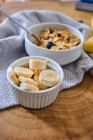 Haferflocken mit Banane, Honig und Walnüssen zum Frühstück, Bananenscheiben mit Haferflocken in einer Schüssel und Bananenfrüchte im Hintergrund