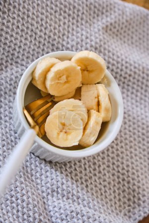Foto de Harina de avena con plátano, miel y nueces para el desayuno, rodajas de plátano con harina de avena en un tazón y fruta de plátano en el fondo - Imagen libre de derechos