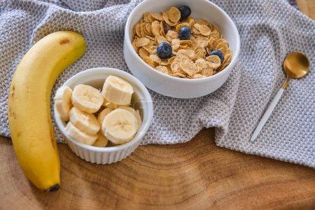 Foto de Harina de avena con plátano, miel y nueces para el desayuno, rodajas de plátano con harina de avena en un tazón y fruta de plátano en el fondo - Imagen libre de derechos