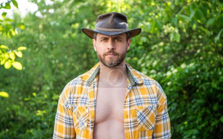 Mann mit Cowboyhut. sexy Mann im karierten Hemd. Westlicher Mann mit Hut.
