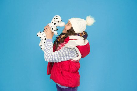 Photo for Kid toy shop. small girl hold dog toy. kid love her fluffy pet puppy. winter activity and fun. childhood happiness. fashion kid turquoise background. child happy to play with toy. - Royalty Free Image