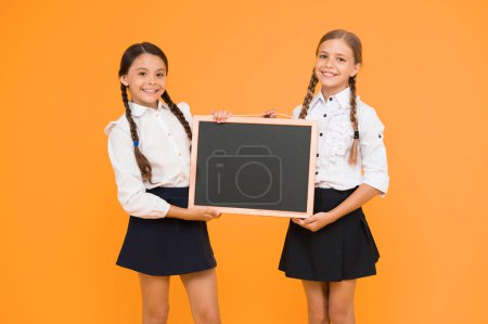 Photo for Got ready. Small pupils. Small girls holding blackboard on yellow background. Small schoolchildren with black-board for education. Small children preparing school chalkboard for lesson, copy space. - Royalty Free Image