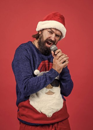 Photo for Happy male hipster with beard and moustache wearing santa hat for xmas party celebration sing christmas song in karaoke, xmas music. - Royalty Free Image