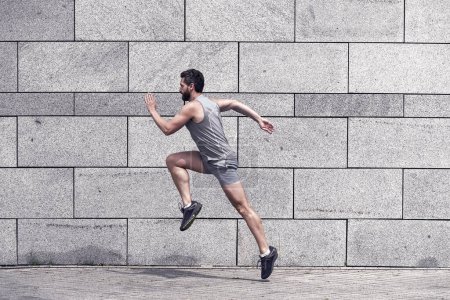 Photo for Male runner. man running to success. sport success. Striving for victory. active man in sport clothing jumping while exercising outdoors. guy sprinting on the street. Leap forward. - Royalty Free Image